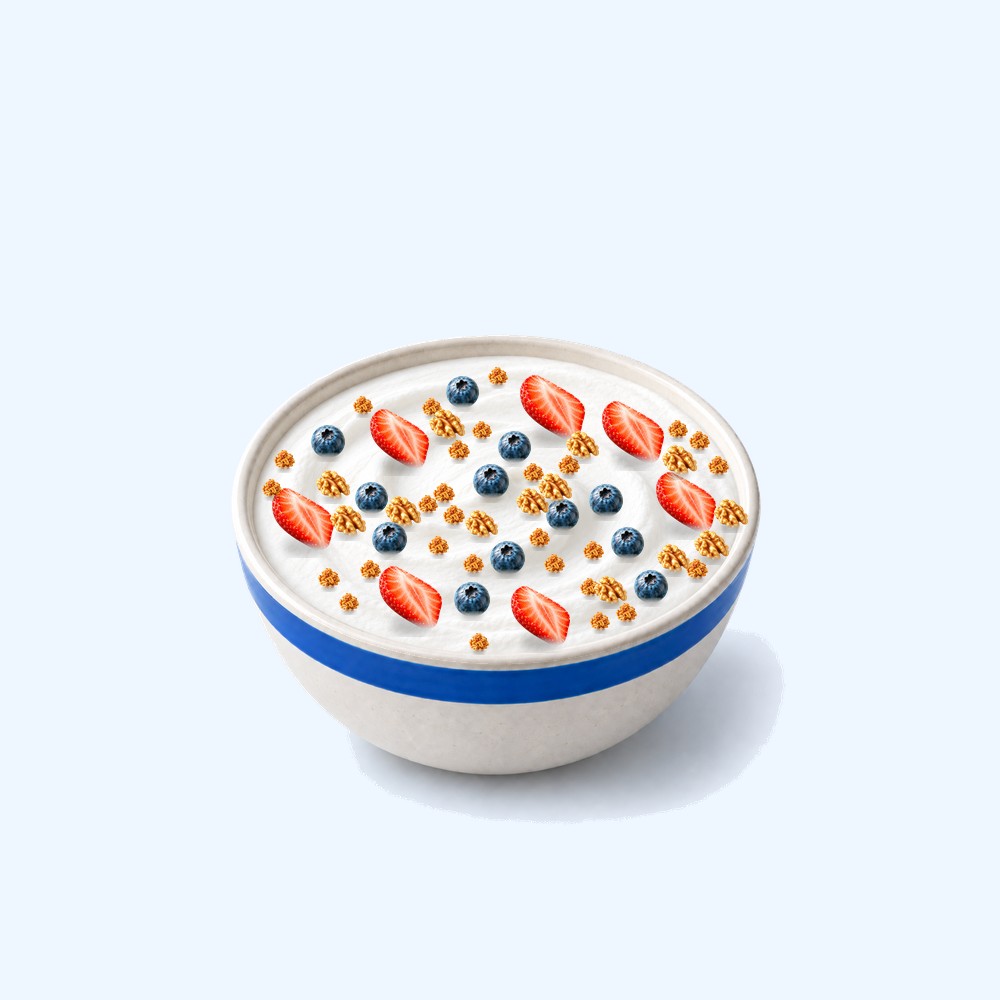 A full bowl of Greek yoghurt with strawberries, blueberries, granola and walnuts.